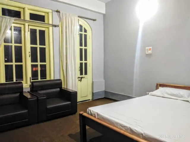 A homestay bedroom with a double bed, armchairs and a wardrobe